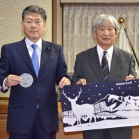 Montbell Chairman Isamu Tatsuno (right) promotes products made by Abashiri Prison inmates during a meeting with Justice Minister Yoshihisa Furukawa at the ministry on Monday. | KYODO