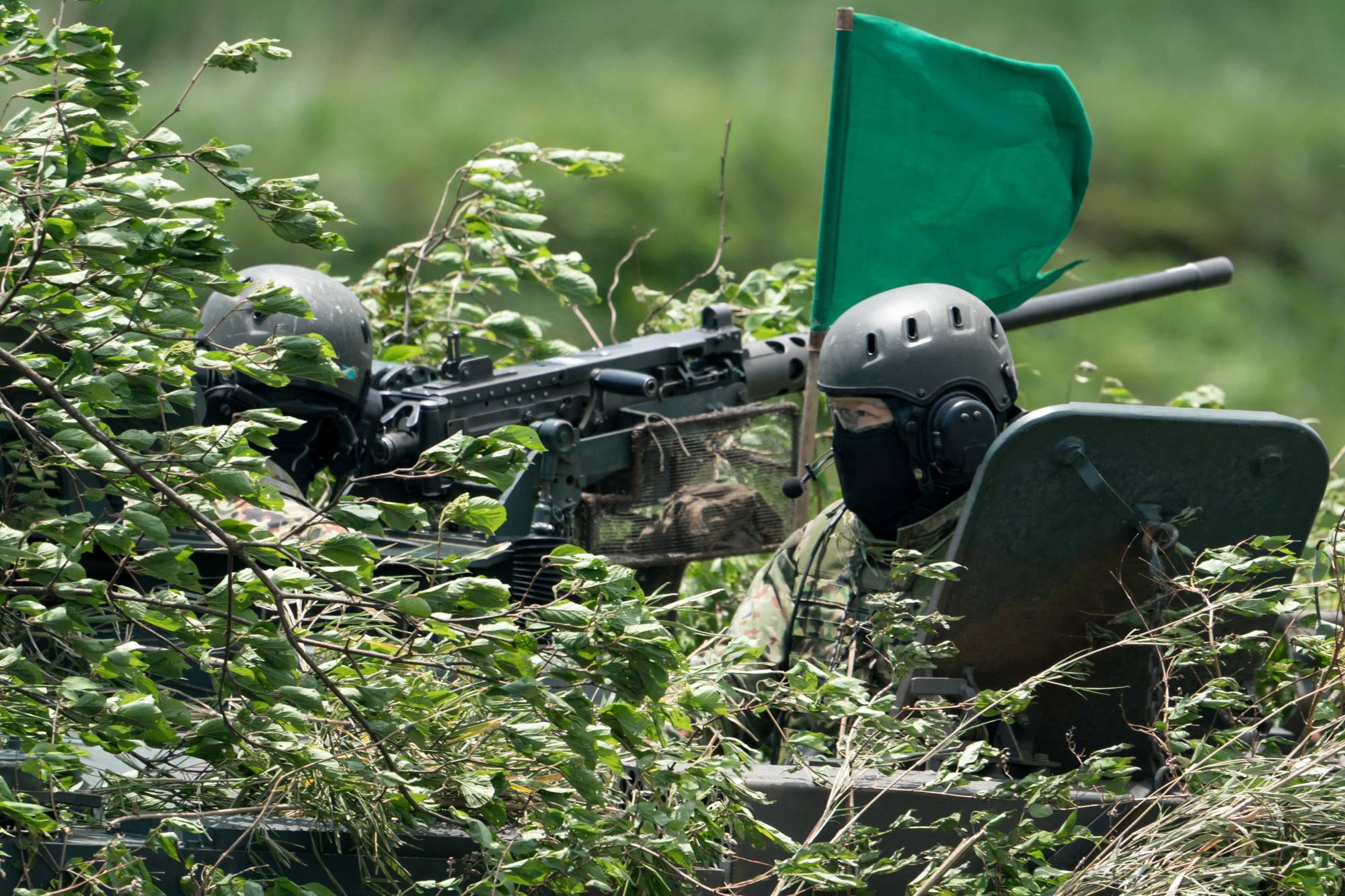 Members of the Ground Self-Defense Force ride on a combat vehicle during a live fire exercise at the East Fuji Maneuver Area in Gotemba, Shizuoka Prefecture, on May 28. | POOL / VIA REUTERS