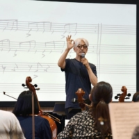 Musician Ryuichi Sakamoto teaches a youth orchestra during summer camp in Yamanashi Prefecture in August 2019. | KYODO
