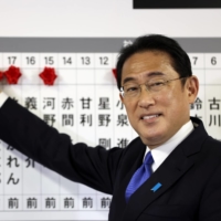 Prime Minister Fumio Kishida smiles as he puts rosettes on a board with names of successful general election candidates at Liberal Democratic Party headquarters in Tokyo last October.    | POOL / VIA REUTERS