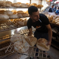 A worker arranges freshly baked bread in a market in Cairo on June 1. | BLOOMBERG