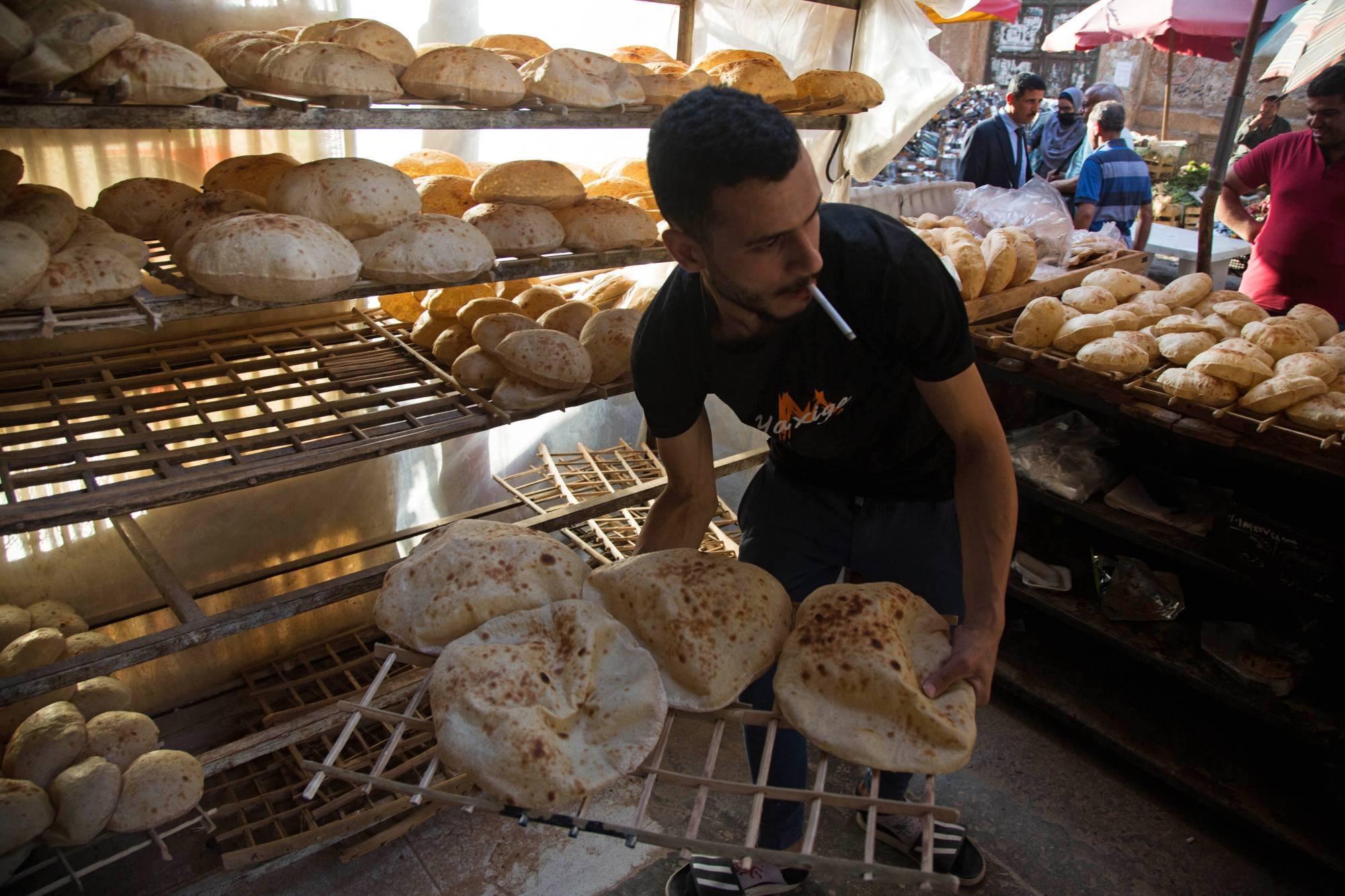 A worker arranges freshly baked bread in a market in Cairo on June 1. | Bloomberg