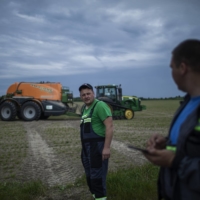 Farmers work a field on the outskirts of Lviv, Ukraine, in May.  | DIEGO IBARRA SANCHEZ / THE NEW YORK TIMES