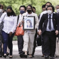 The family of a Sri Lankan woman, who died while in custody at an immigration center, and supporters head to the Nagoya District Court with her photo in Nagoya on Wednesday. | KYODO