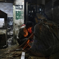 A worker welds an excavator bucket at a heavy machinery repair workshop in Ahmedabad, Gujarat, India, in November 2017.  | BLOOMBERG