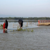 People make their way through a flooded road after heavy rains in Sylhet, Bangladesh, in May. | AFP-JIJI