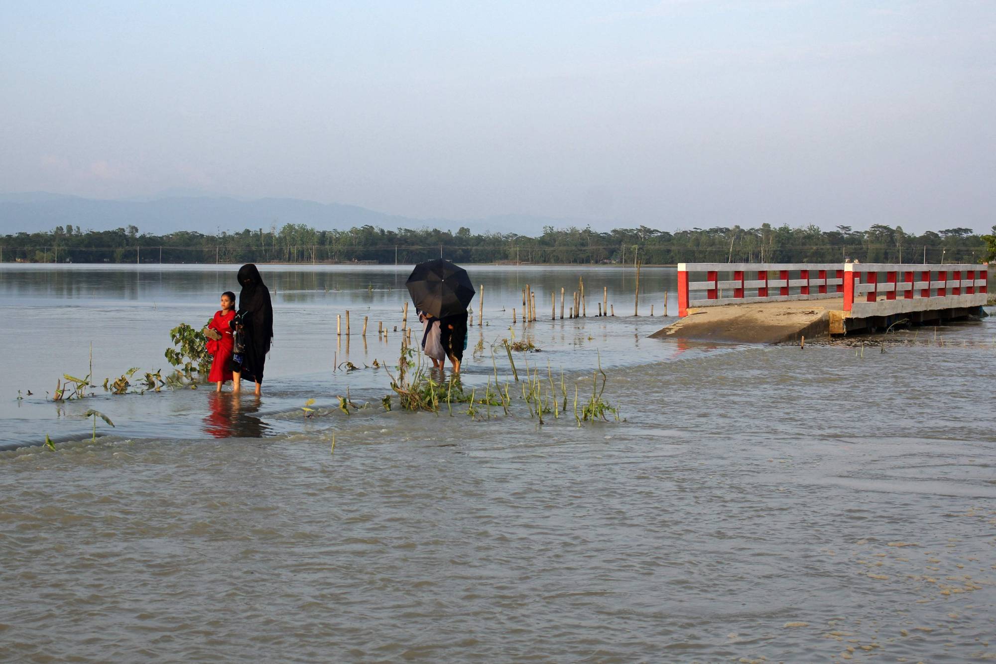 People make their way through a flooded road after heavy rains in Sylhet, Bangladesh, in May. | AFP-Jiji