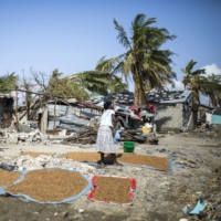 A woman lays out rice grain to dry in the sun following the cyclone in Beira, Mozambique, in March 2019.  | BLOOMBERG