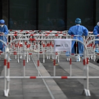 Health workers wait at a COVID-19 testing site in Beijing on Sunday. | AFP-JIJI