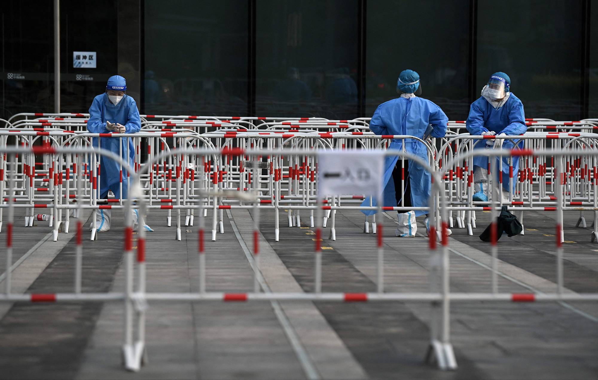 Health workers wait at a COVID-19 testing site in Beijing on Sunday. | AFP-JIJI