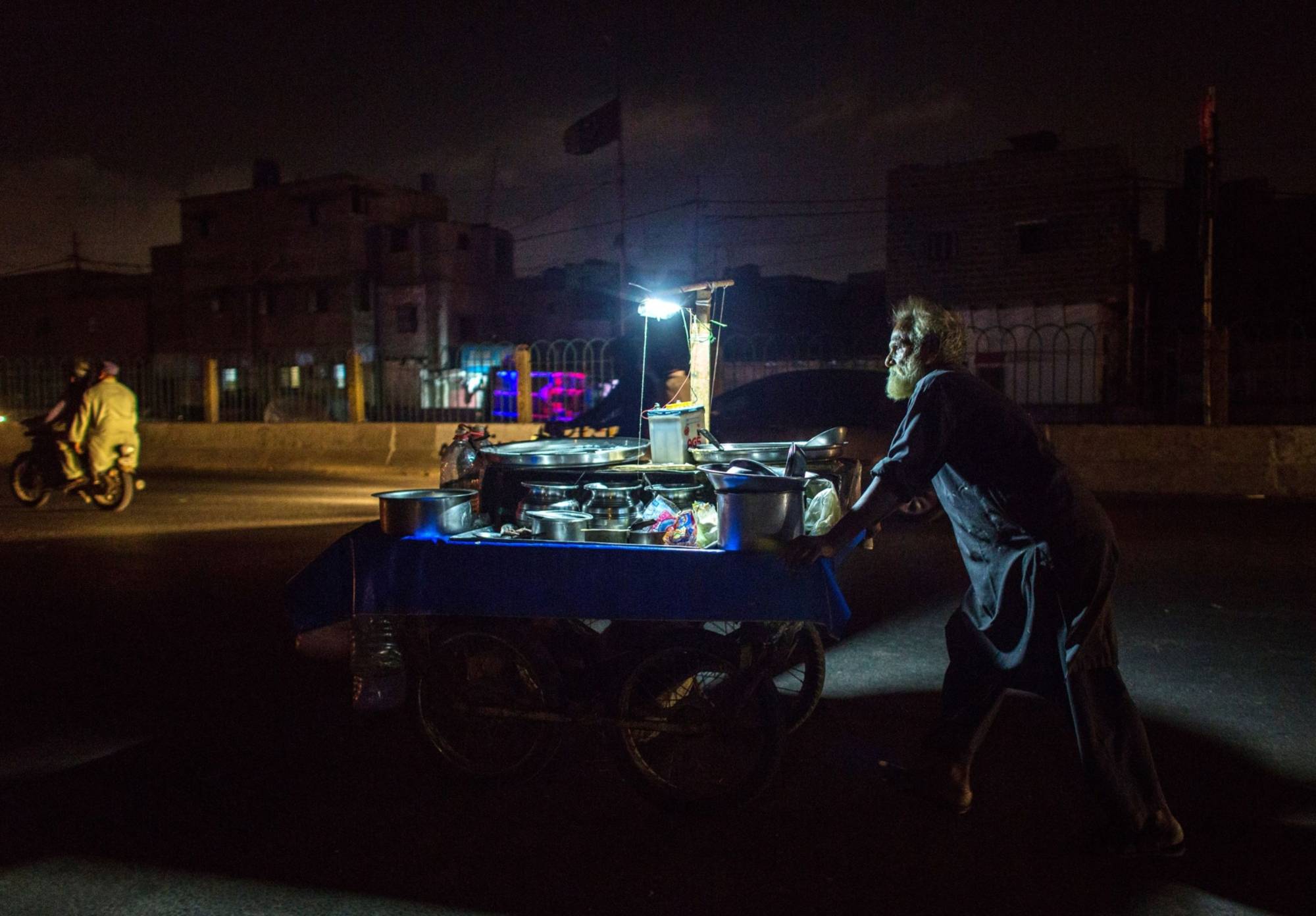 A street vendor in Karachi pushes his cart during a blackout in on Wednesday.  | BLOOMBERG
