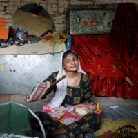 Farmer Waderi, 17, fans her 1-month-old son Amar Kumar on the outskirts of Jacobabad, Pakistan, on May 17. | REUTERS