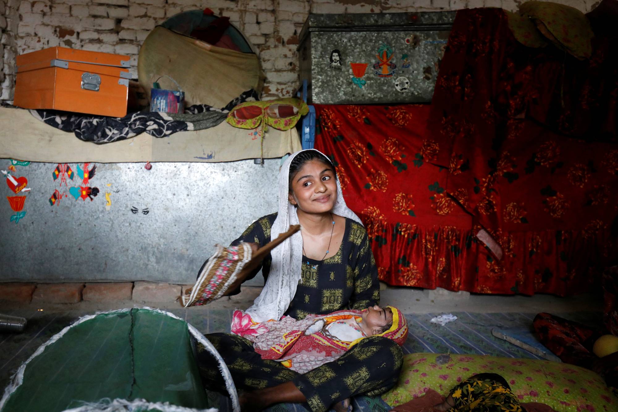 Farmer Waderi, 17, fans her 1-month-old son Amar Kumar on the outskirts of Jacobabad, Pakistan, on May 17. | REUTERS