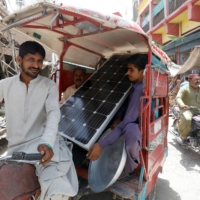 People in a rickshaw carry a solar panel on May 14. | REUTERS