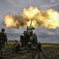 Ukrainian servicemen fire a French self-propelled 155-millimeter (52-calibre) Caesar gun towards Russian positions at a front line in the eastern Ukrainian region of Donbas on Wednesday. Ukraine pleaded with Western governments on Wednesday to decide quickly on sending heavy weapons to shore up its faltering defenses. | AFP-JIJI