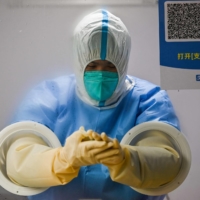 A health worker prepares to take swab samples to test for COVID-19, in Shanghai, on Monday. |  AFP-JIJI