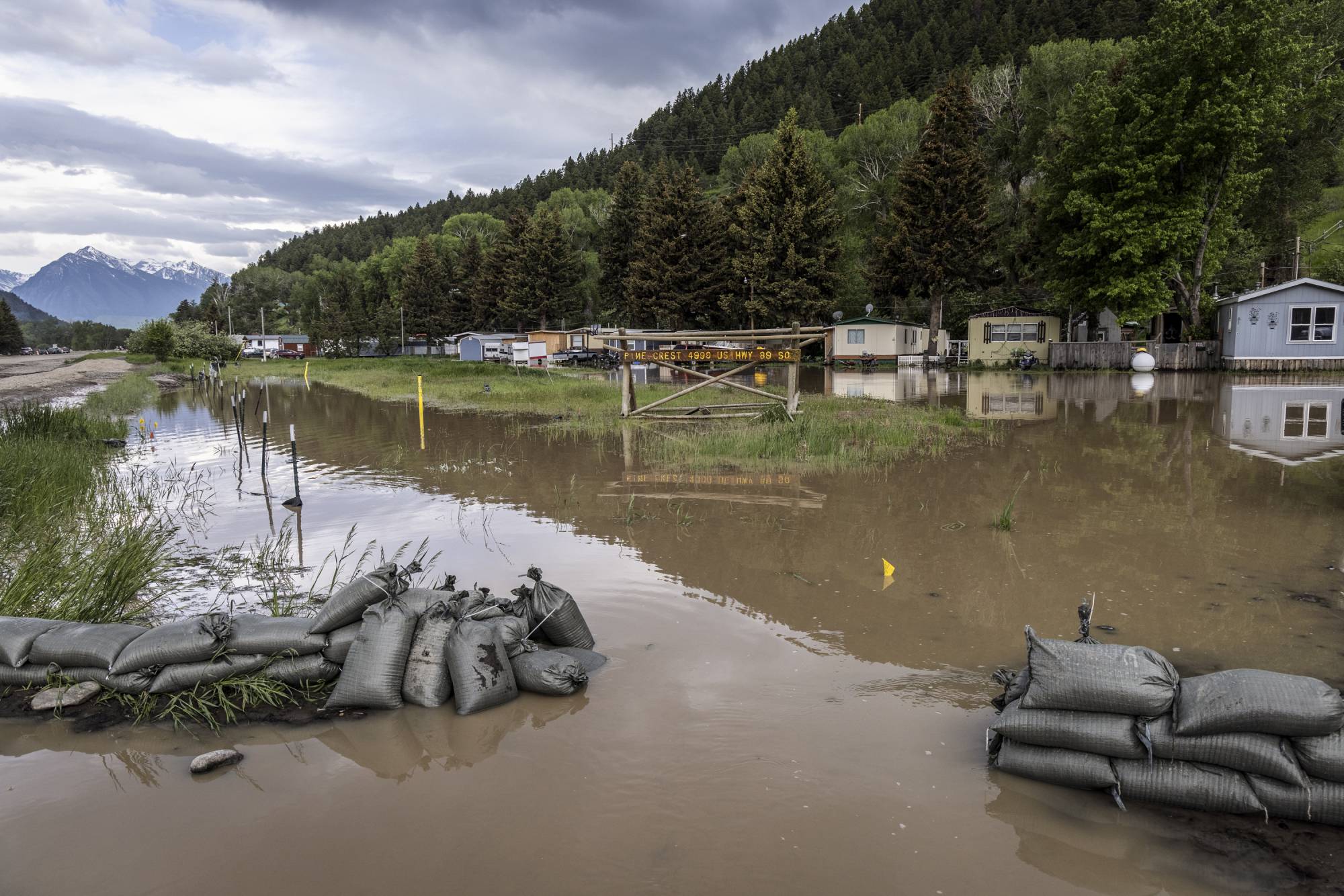 Floodwater breaches sandbags stacked by the roadside north of Yellowstone National Park on Tuesday. The most severely damaged northern section of the park may stay closed for the rest of the season. | Louise Johns / The New York Times