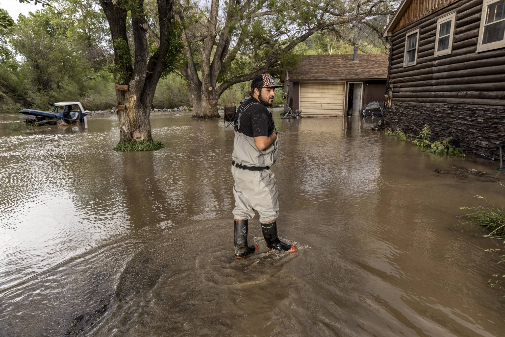 Patrick Grey wades through floodwater outside his home near Yellowstone National Park on Tuesday. | Louise Johns / The New York Times