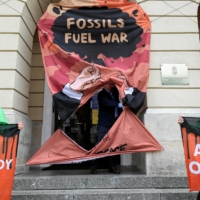 Greenpeace activists hold banners with slogans in English and Hungarian during a protest against Hungarian fossil fuel supplies from Russia, in front of the Hungarian embassy in Warsaw on May 25. The slogan in Hungarian reads: \'Enough of the red oil.\'  | REUTERS 