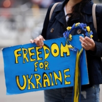 A climate change activist holds a sign during a protest in front of the European Council to call the EU for an immediate embargo on Russian oil and gas, as Russia\'s invasion of Ukraine continues, in Brussels on April 29. | REUTERS