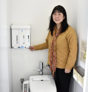 Eri Sugita, an associate professor of international cooperation studies at Osaka University, shows a cardboard dispenser for sanitary products that she developed. | KYODO