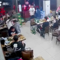 A man assaults a woman at a restaurant in Tangshan, China, on June 10. China is launching an investigation into a group of police officials over their handling of the attack. | REUTERS