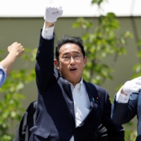 Prime Minister Fumio Kishida, who concurrently serves as leader of the ruling Liberal Democratic Party, raises his fist from the top of an election campaign van in Kawasaki on Friday. | REUTERS