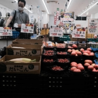 A customer selects vegetables at a market in Ikeda, Osaka Prefecture, on June 18. | BLOOMBERG