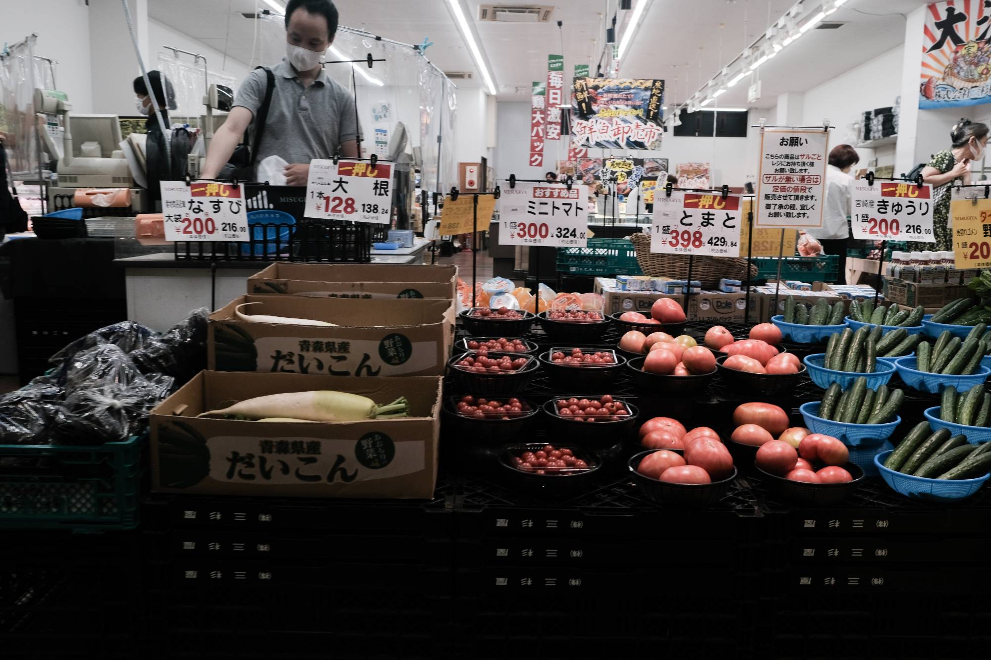A customer selects vegetables at a market in Ikeda, Osaka Prefecture, on June 18. | Bloomberg