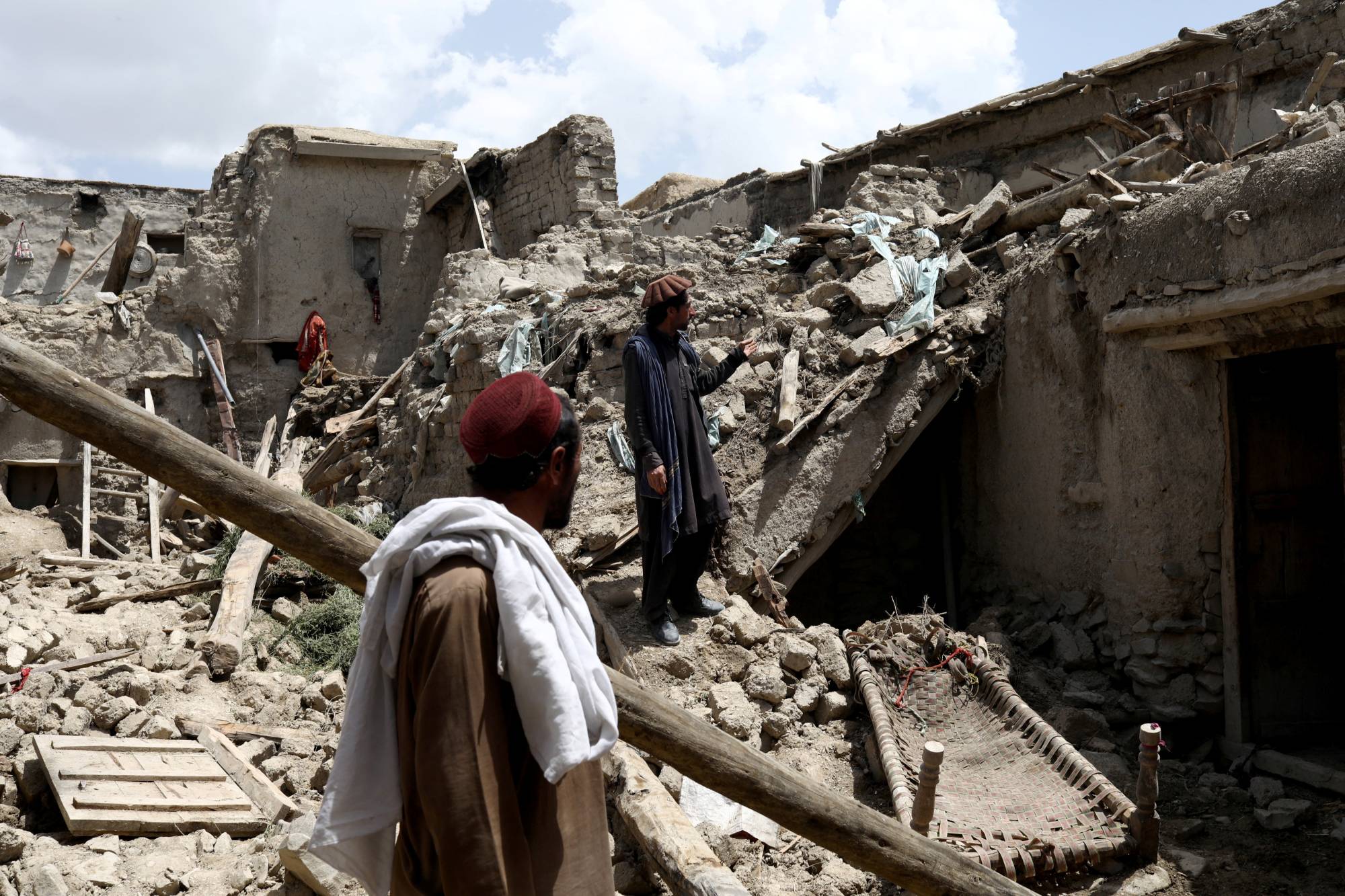 Men stand on the debris of a house that was destroyed by an earthquake in Gayan, Afghanistan, on Thursday. | REUTERS 