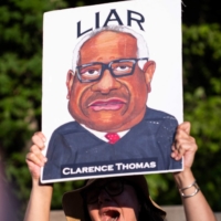 A demonstrator holds a sign during protests at the entrance of the gated community where U.S. Supreme Court Justice Thomas Clarence lives in Fairfax, Virginia, after the court struck down the right to abortion on Friday. | AFP-JIJI
