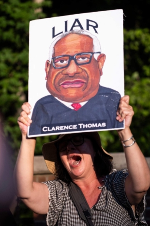 A demonstrator holds a sign during protests at the entrance of the gated community where U.S. Supreme Court Justice Thomas Clarence lives in Fairfax, Virginia, after the court struck down the right to abortion on Friday. | AFP-JIJI