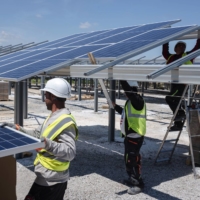 Workers install solar panels at a solar park in Laudun L\'Ardoise, France, in June 2021.  | BLOOMBERG
