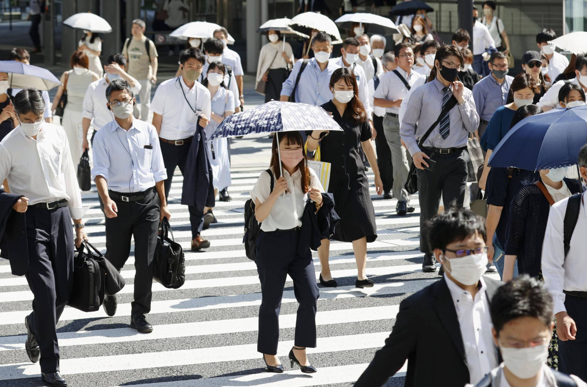 Most people wear masks even under sweltering heat in Tokyo on Monday. | KYODO