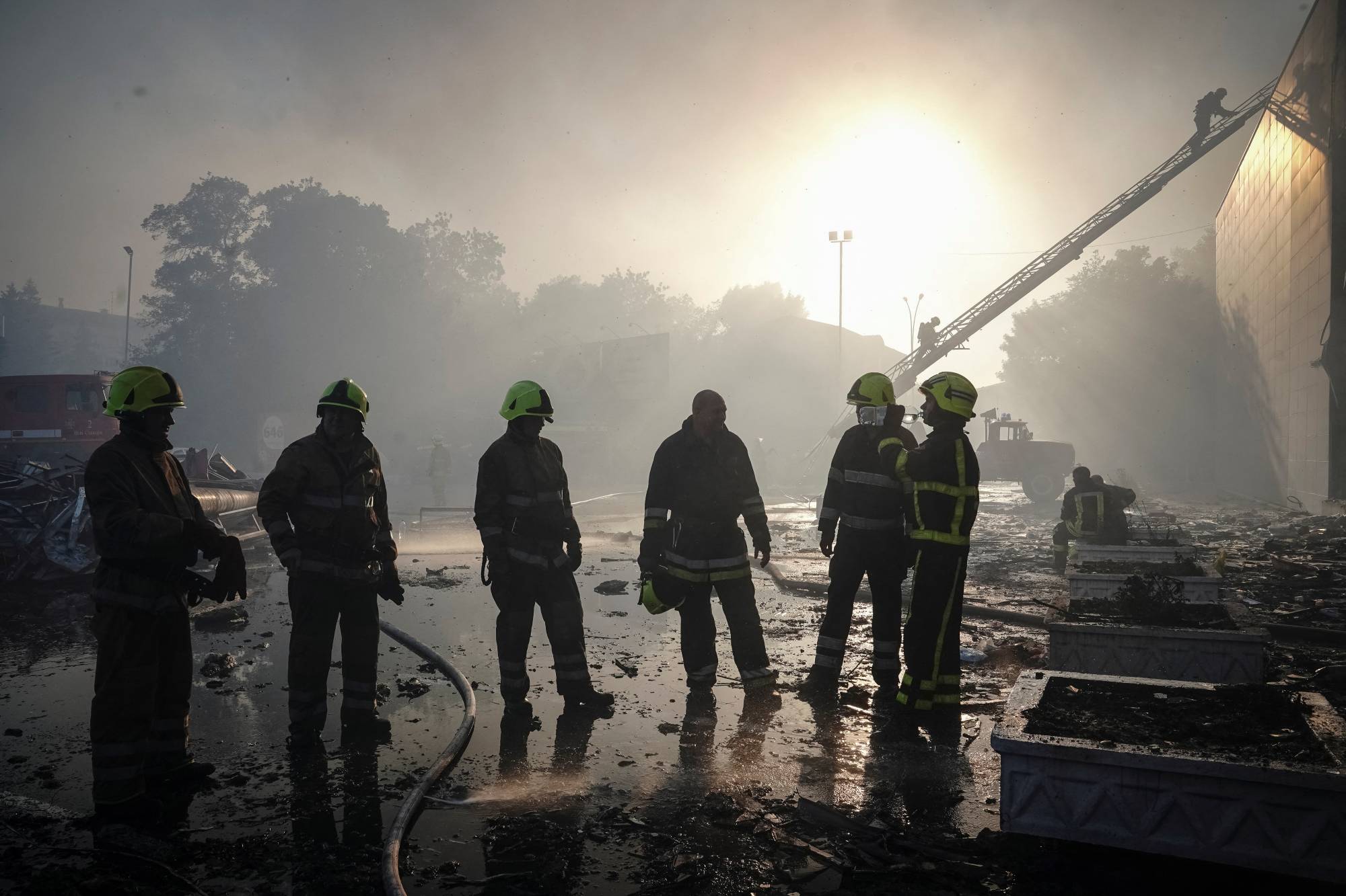 Rescuers pause to rest at a shopping mall hit by a Russian missile strike, in the Poltava region of Ukraine on Monday.  | REUTERS