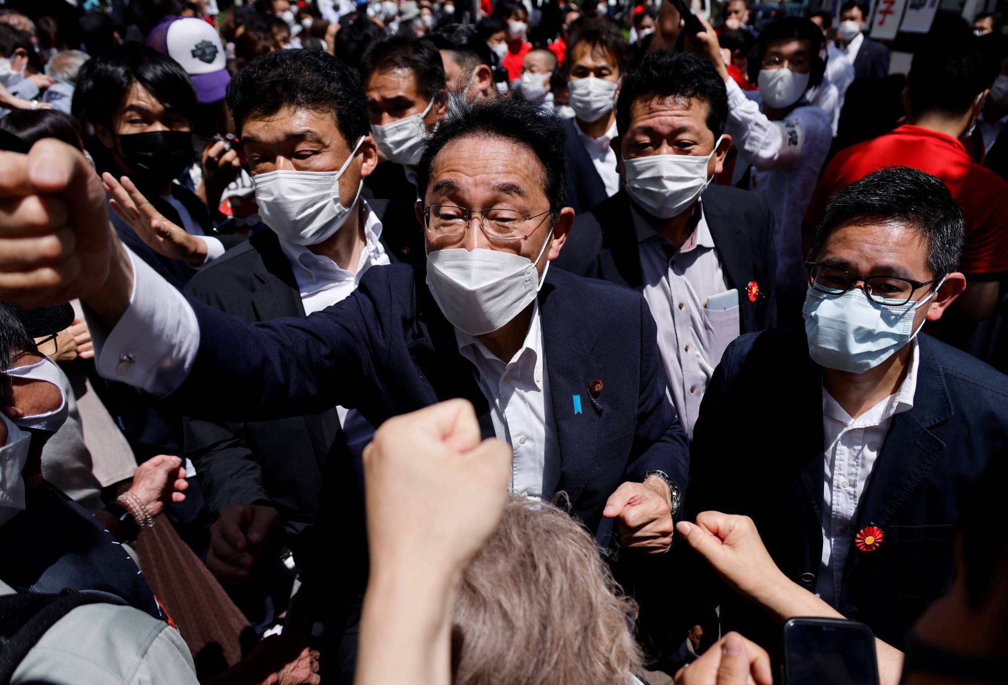 Prime Minister Fumio Kishida bumps fists with voters after delivering a speech on June 24. | REUTERS