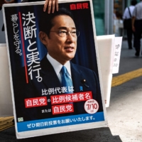 A voter holds a placard showing Kishida after a campaign stop by Liberal Democratic Party member Keiichiro Asao in Yokohama on June 24. | AFP-JIJI