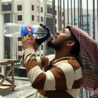 A foreign laborer drinks water at a construction site in the Omani capital Muscat amid scorching heat on June 21. | AFP-JIJI