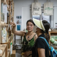 Yu Yuan (left) attends to a customer at her shop, The Bulk House, in Beijing on Thursday.  | BLOOMBERG