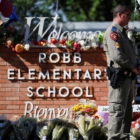 A public safety officer stands guard in front of a memorial at Robb Elementary School in Uvalde, Texas, on May 26, two days after a gunman killed 19 children and two adults at the facility. | REUTERS
 