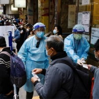 People queue up at a COVID-19 community testing center in Hong Kong in February. | REUTERS