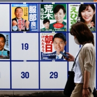 A woman walks past candidates\' posters for the Upper House election, in Tokyo on June 22. | REUTERS