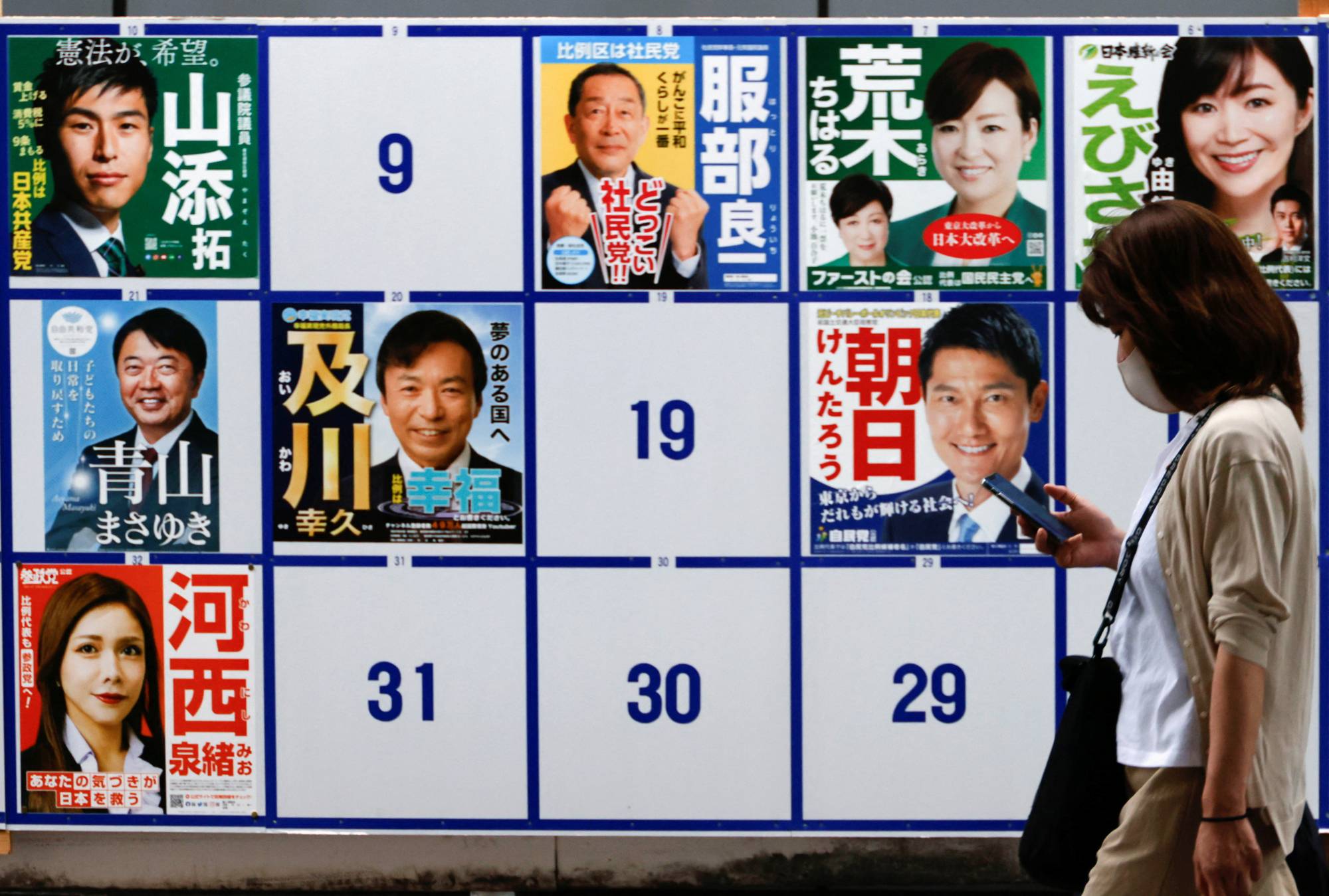 A woman walks past candidates' posters for the Upper House election, in Tokyo on June 22. | REUTERS