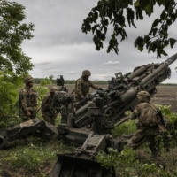 Ukrainian troops load a Howitzer M777 155mm artillery piece in the Donetsk region of eastern Ukraine on May 22. | IVOR PRICKETT / THE NEW YORK TIMES