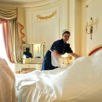 A chambermaid changes the sheets on a bed at The Ritz hotel in London in 2006. In order to attract more workers, hoteliers are offering higher pay, free accommodation and perks like bonuses and health insurance. | REUTERS