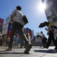 People walk in Osaka\'s Minami district on June 29. About 70% of June\'s heat-linked hospital referrals were registered in the week between June 24 and 30, when the population sweated through a heat wave. | KYODO