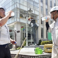 Road construction workers hydrate with sports drinks in Maebashi, Gunma Prefecture, on June 29. | KYODO