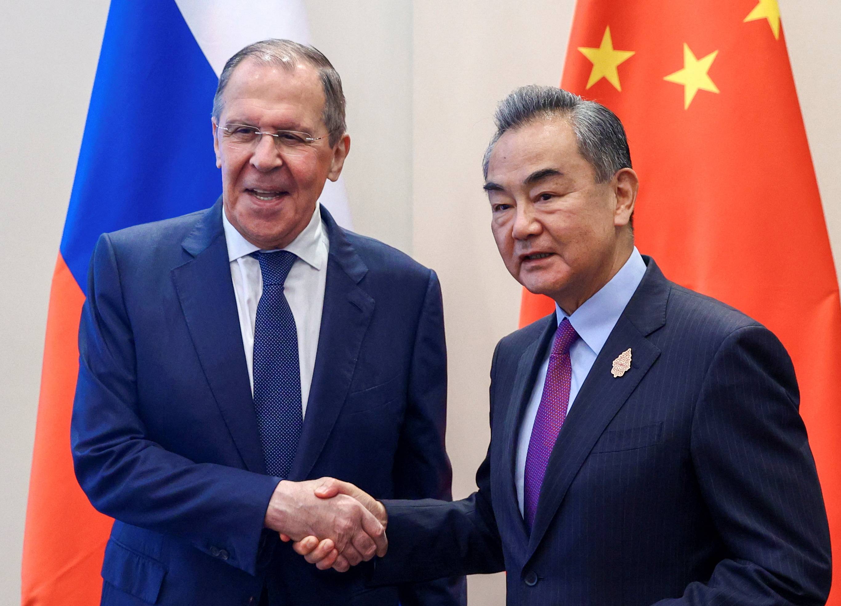 Russian Foreign Minister Sergei Lavrov (left) and Chinese Foreign Minister Wang Yi shake hands as they meet in Denpasar, Indonesia, on Thursday | RUSSIAN FOREIGN MINISTRY / VIA REUTERS 