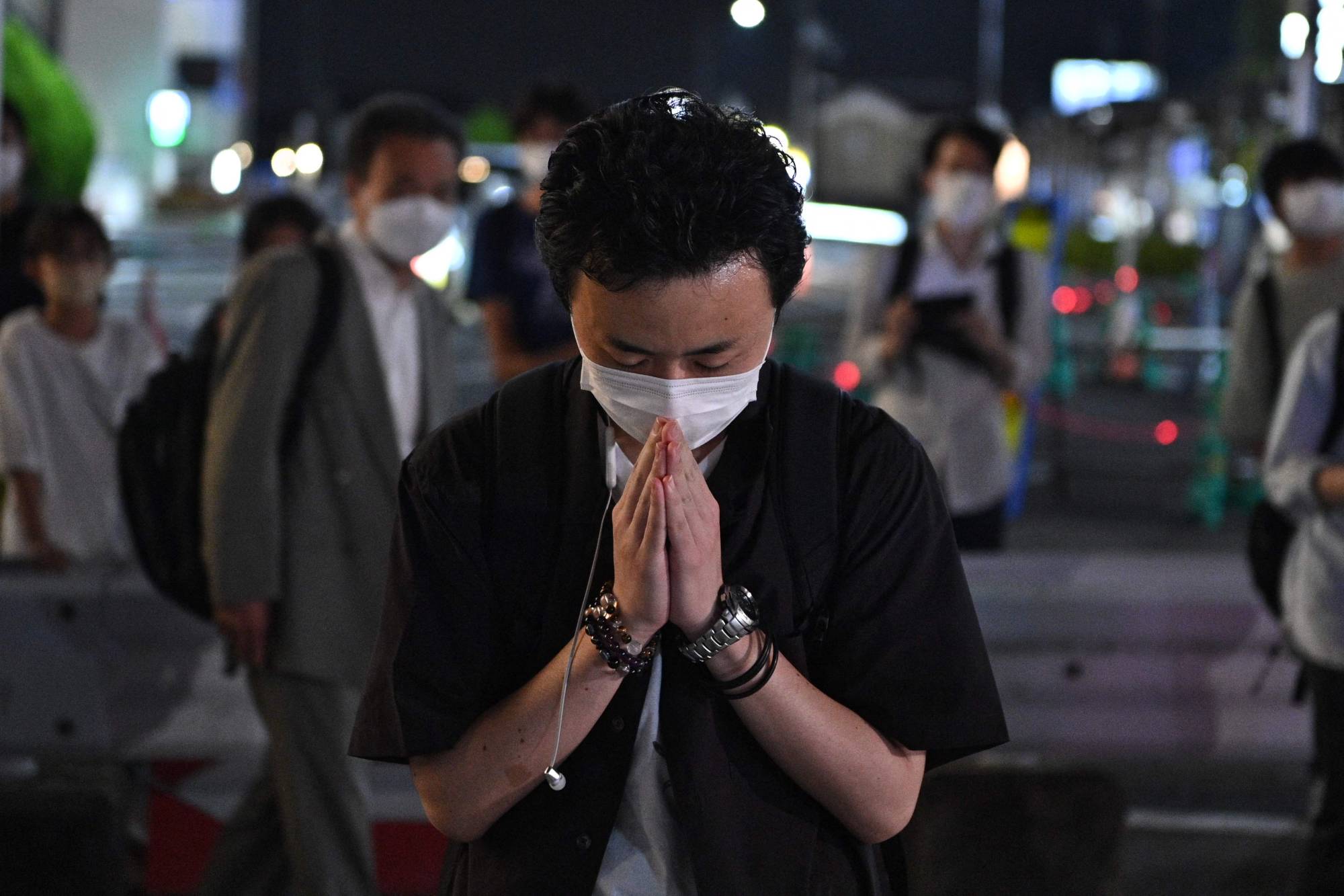 A man prays on Friday evening near Yamato-Saidaiji Station in Nara where Abe was shot earlier in the day. | AFP-JIJI