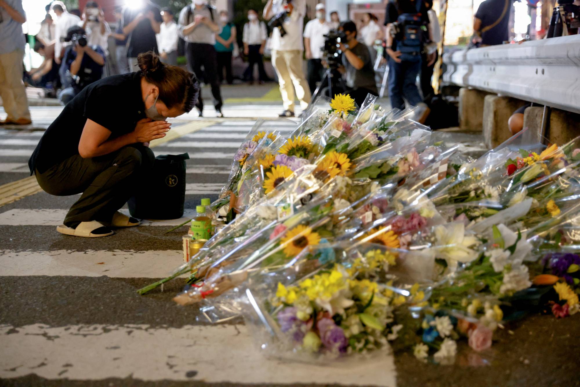 A woman prays at the site were Abe was shot while campaigning for the upcoming upper house election. | REUTERS